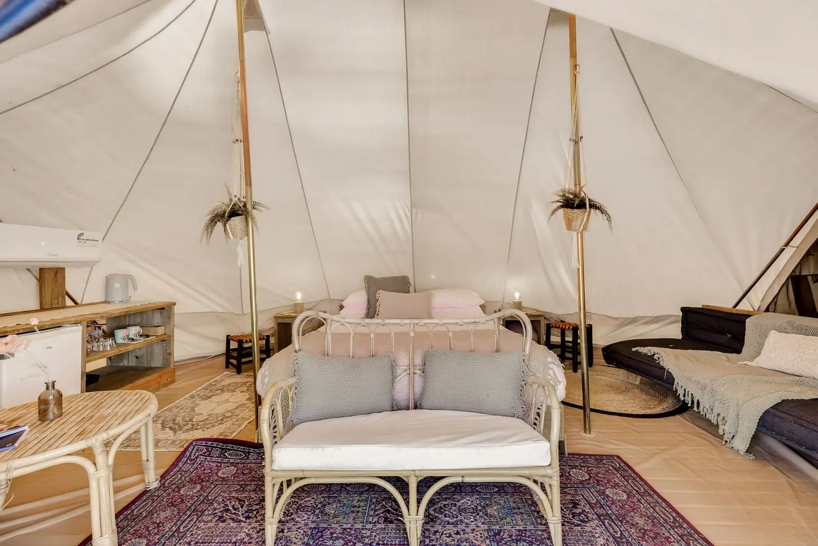 Inside a double-pole bell tent with a queen bed and couch