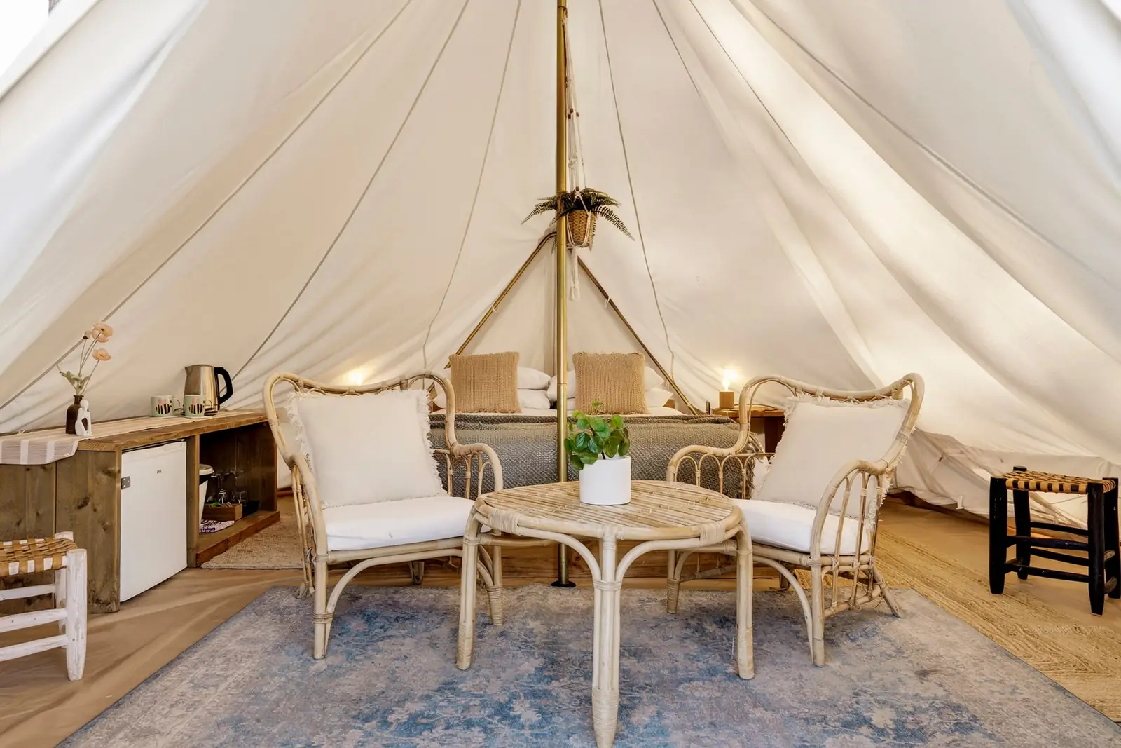 Inside a single-pole bell tent with rattan chairs and a drink station