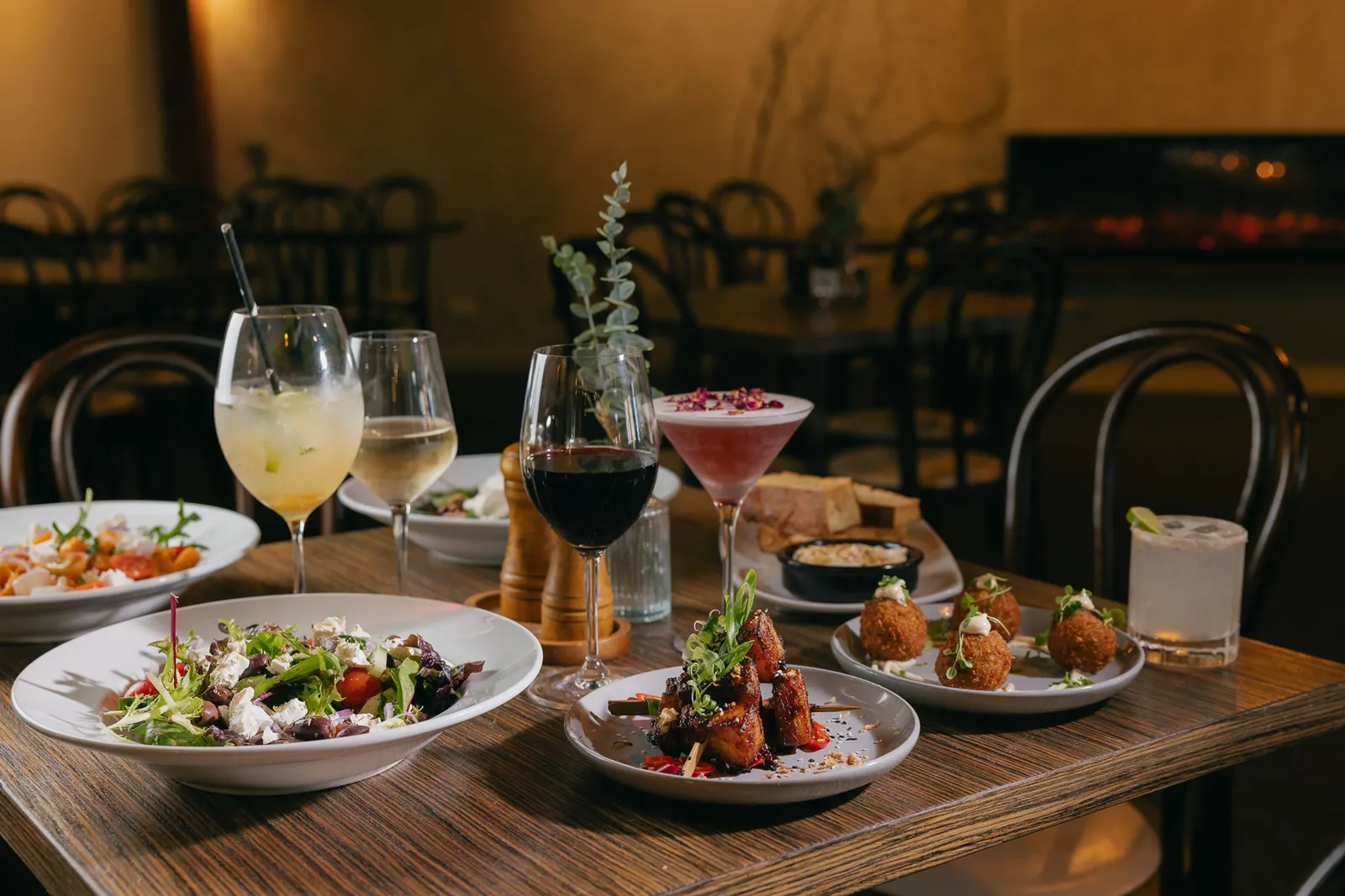 Shared plates, cocktails and wine on a table in the dining room